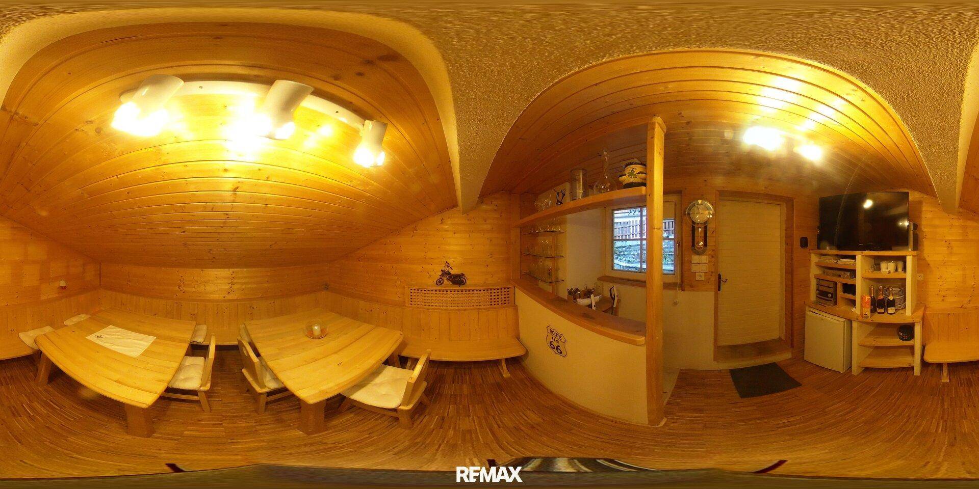 Gemütlicher Dachbodenraum mit Holzvertäfelung, Essbereich und Fernseher.
