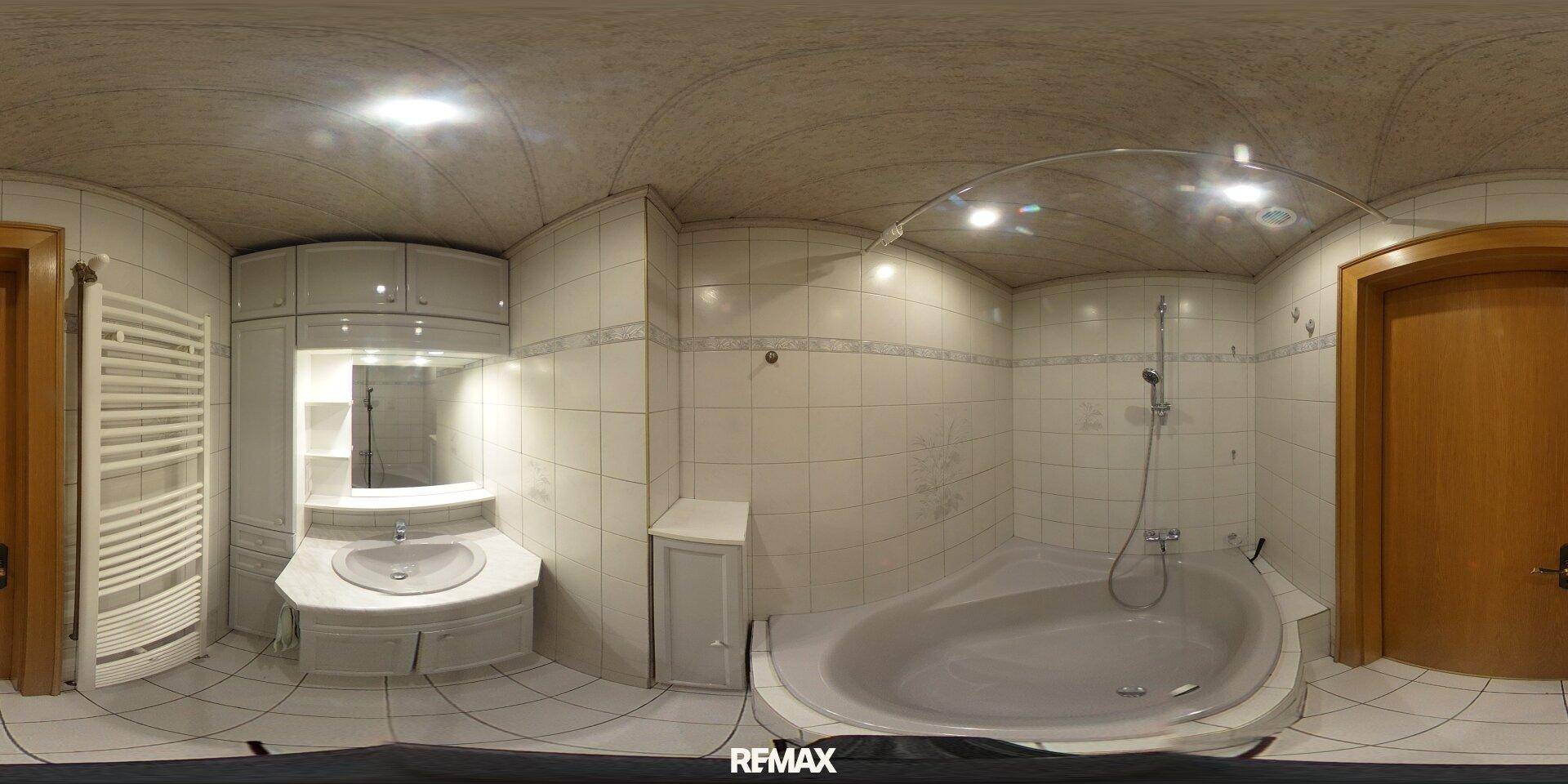 Badezimmer mit Fliesen, Badewanne, Waschbecken und beheiztem Handtuchhalter.