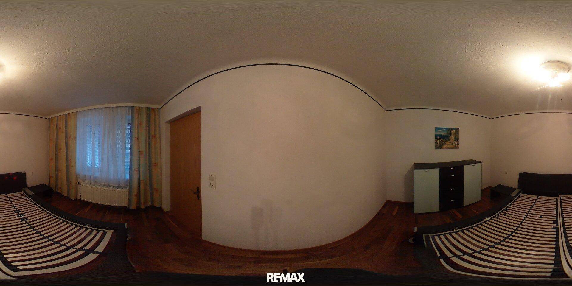 Schlafzimmer mit Holzboden, Fenster und Platz für zwei Betten.