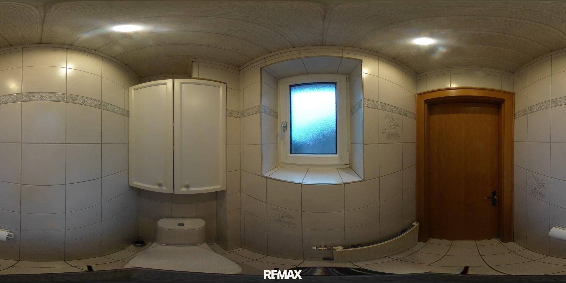 Kleines WC mit weißen Fliesen, Toilette und einem kleinen Fenster.