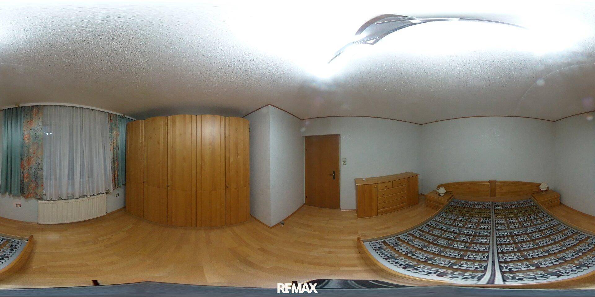 Geräumiges Schlafzimmer mit Holzboden, Einbauschränken und Fenster.