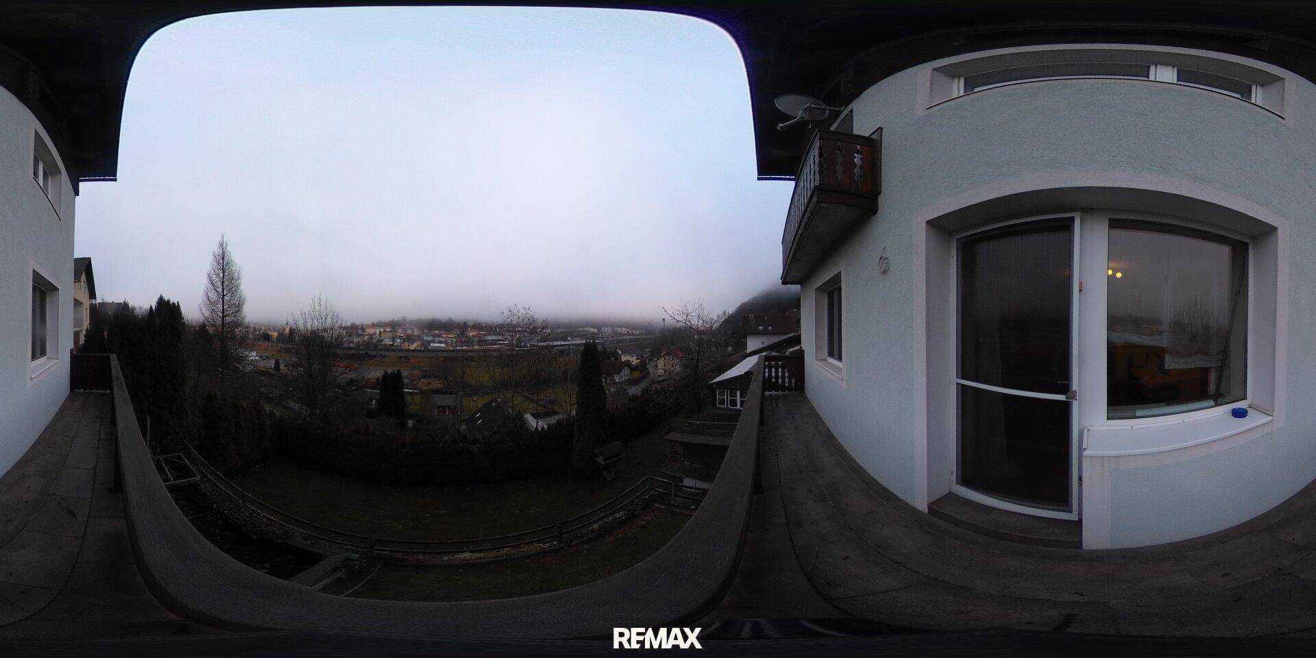 Balkon mit weitem Blick über die Landschaft und die umliegende Siedlung.