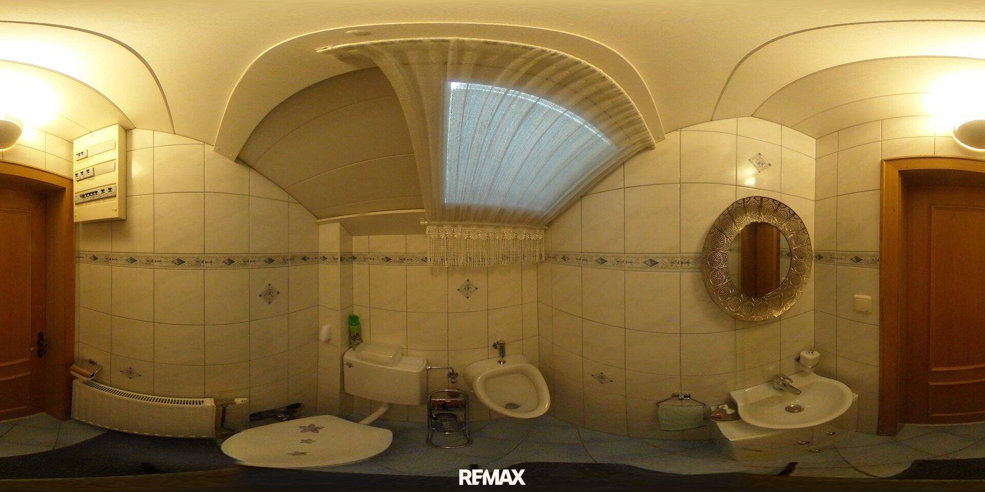 Kleines Gäste-WC mit Fliesen, Bidet, Waschbecken und einem kleinen Fenster für natürliche Belüftung.