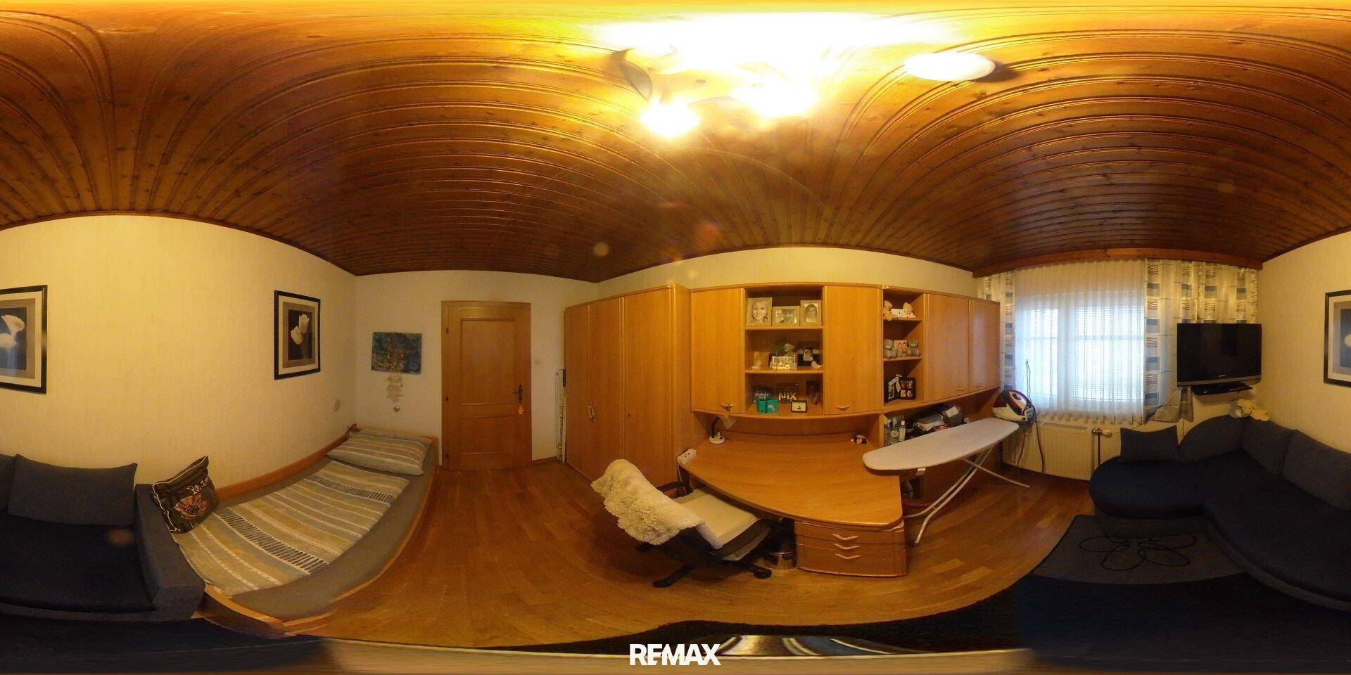 Funktionales Arbeitszimmer mit Holzdecke, Sofa, Schreibtisch und integrierten Regalen für Bücher.