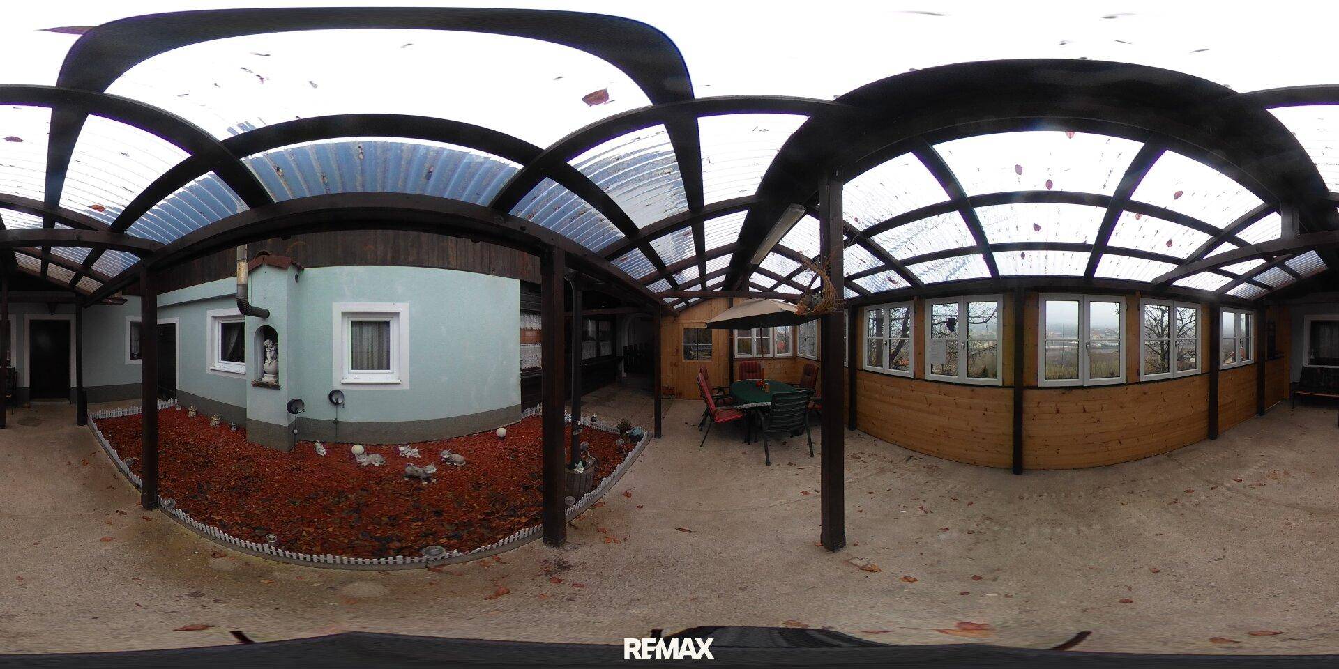 Großer überdachter Außenbereich, möglicherweise ein Wintergarten, mit Sitzgelegenheiten und Gartenhaus.