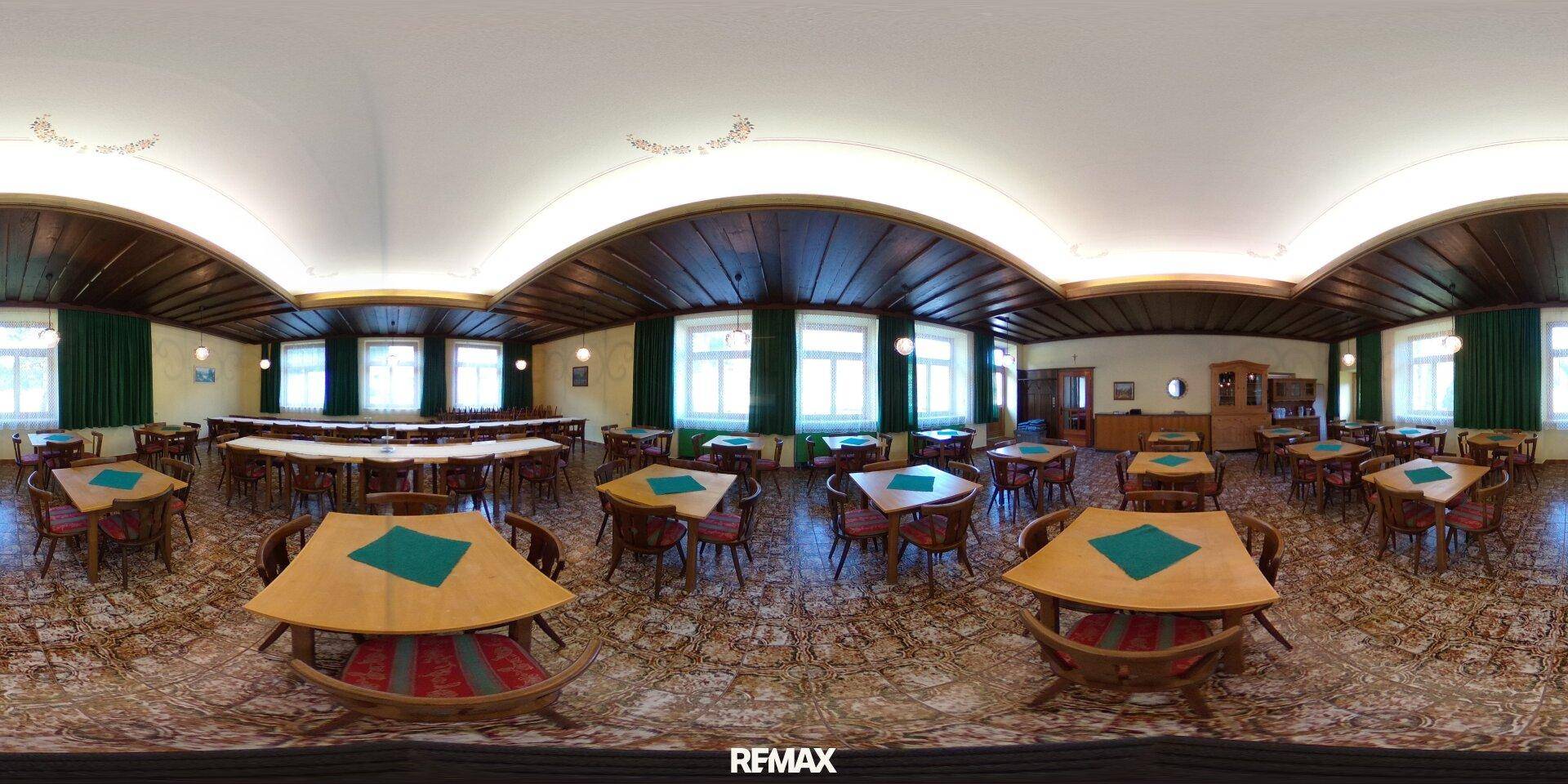 Großer Speisesaal mit vielen Holztischen und Stühlen, traditioneller Einrichtung und Fenstern.