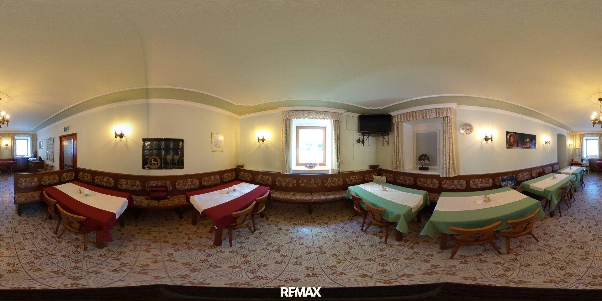Panoramablick auf einen weiteren Speisesaal mit traditionellen Holzbänken, Tischen und gemustertem Fliesenboden.