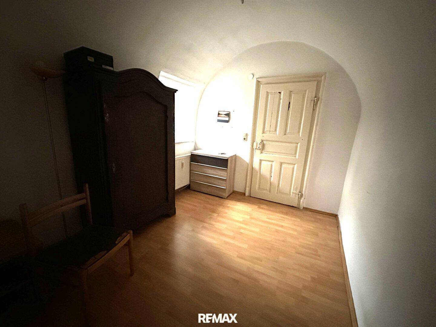 Kleiner Raum mit Holzboden, gewölbter Decke und einem Schrank, ideal als Schlafzimmer.