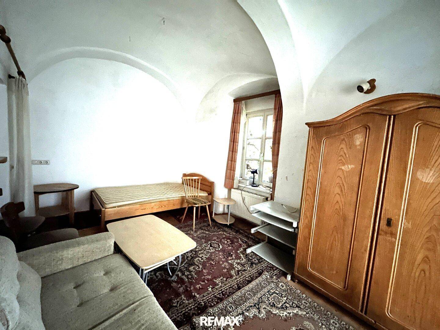 Geräumiger Wohnraum mit gewölbter Decke, Holzboden und traditionellen Möbeln.