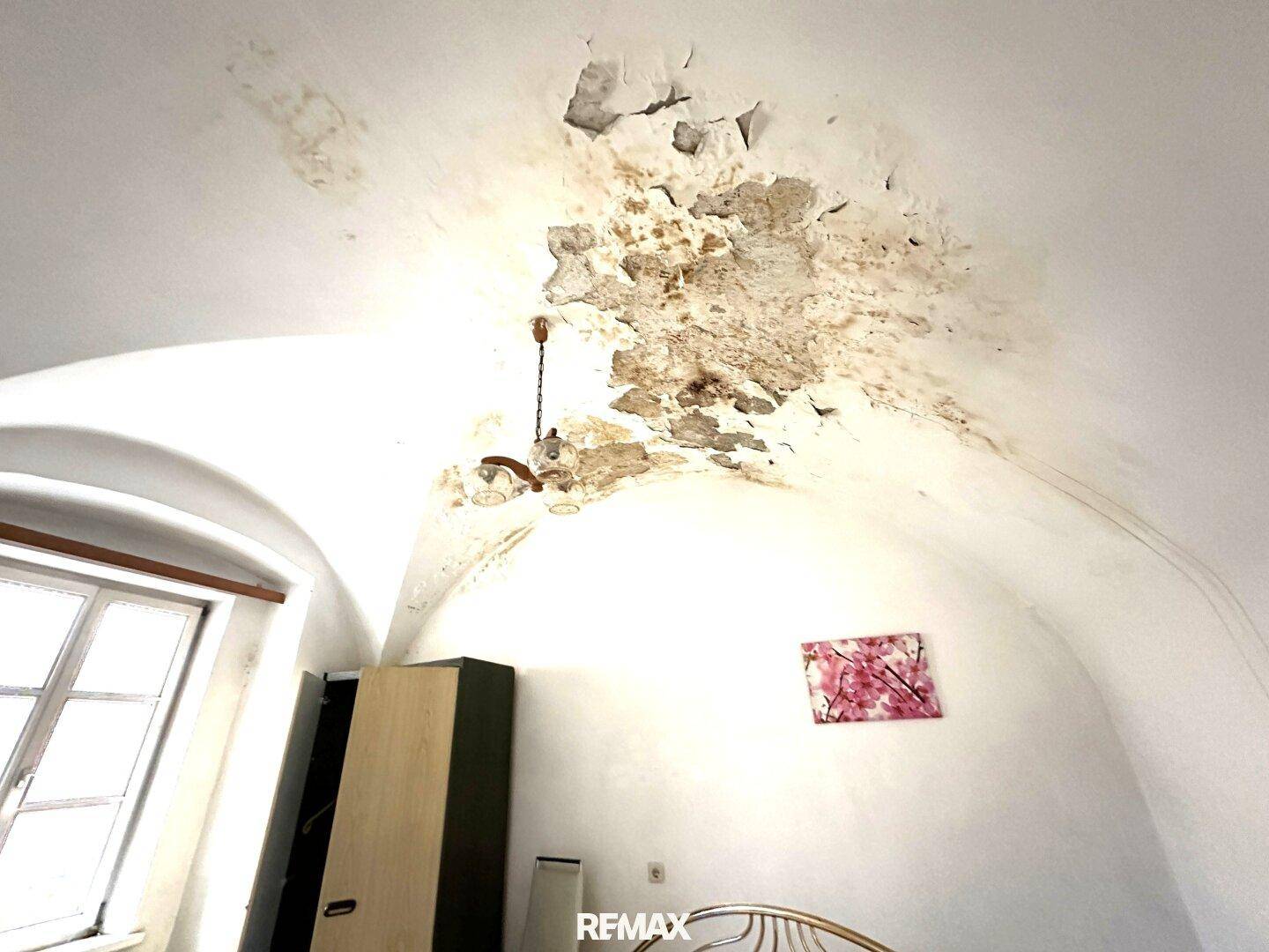 Schlafzimmer mit gewölbter Decke und sichtbaren Putzschäden, bereit für Renovierung.