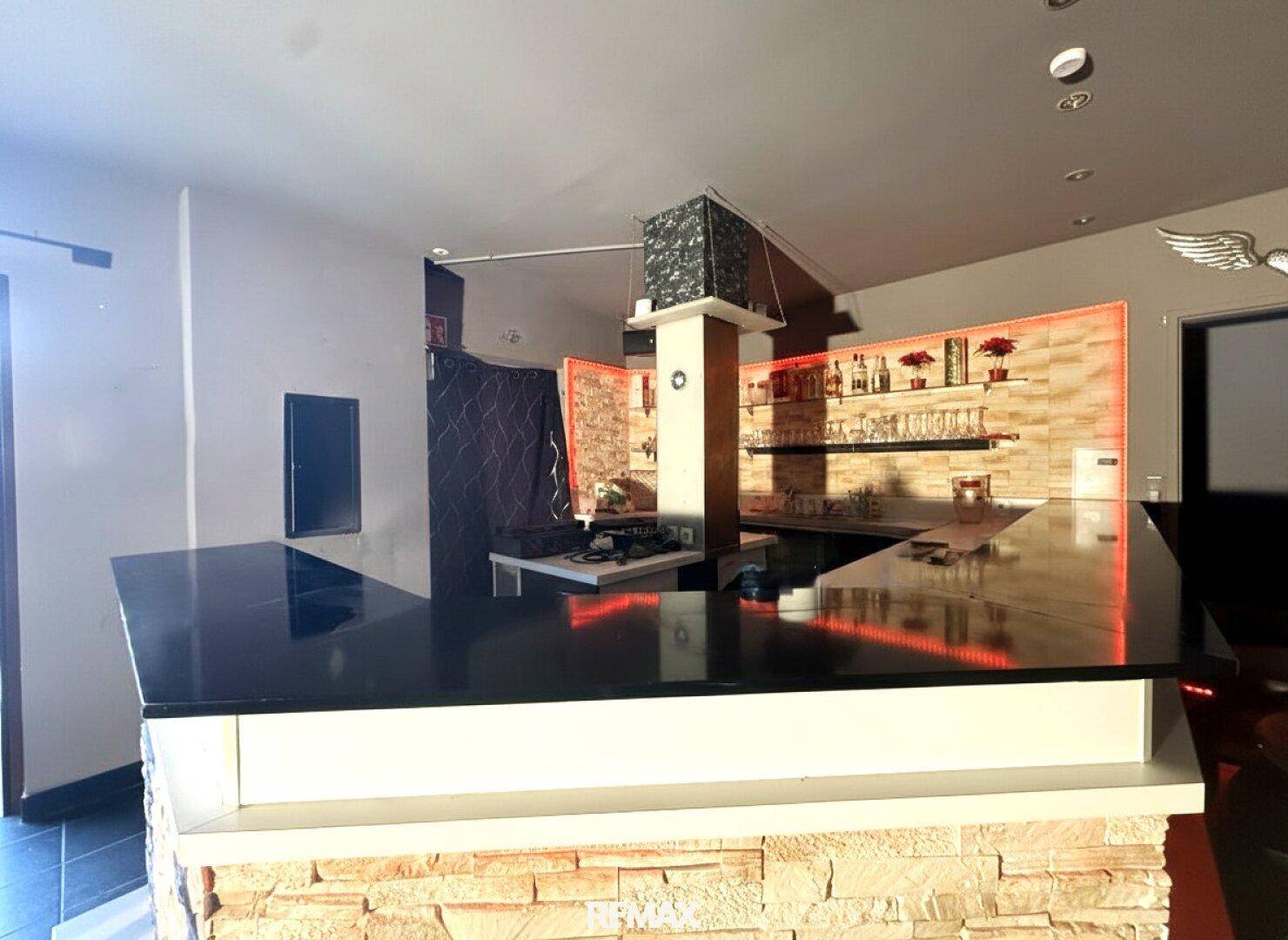 Moderne Bar mit schwarzer Theke und Steinwandverkleidung.