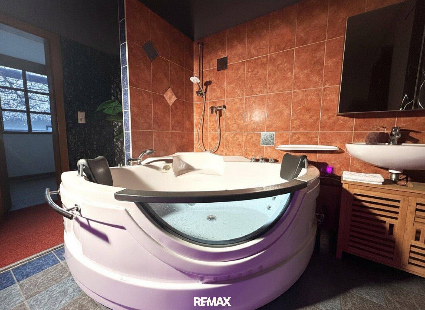 Badezimmer mit großem Whirlpool und rustikalen Wandfliesen.