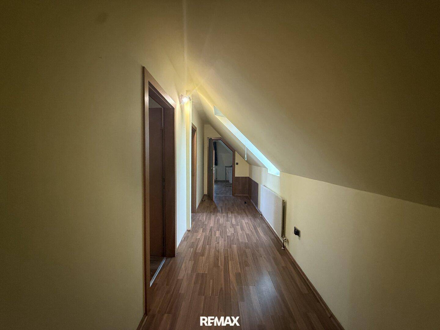 Heller Flur im Dachgeschoss mit Laminatboden und schräger Decke.