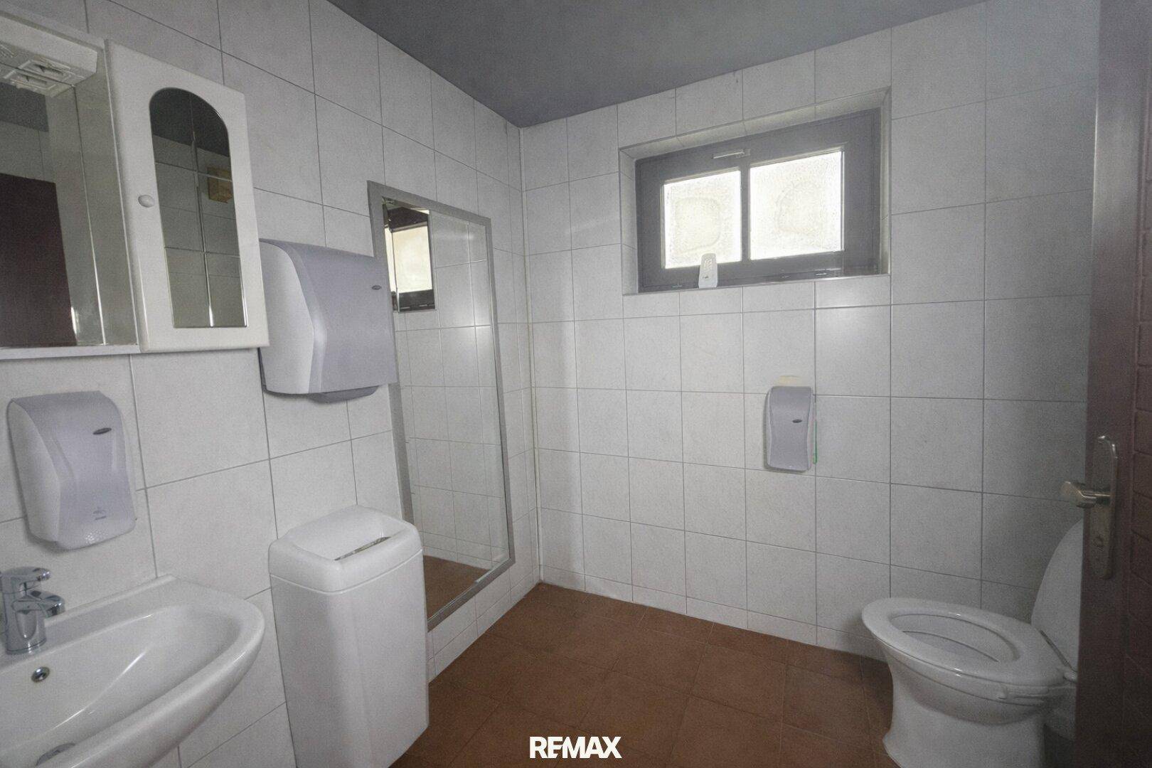 Funktionales WC mit Waschbecken, Toilette und Fenster, gefliest.