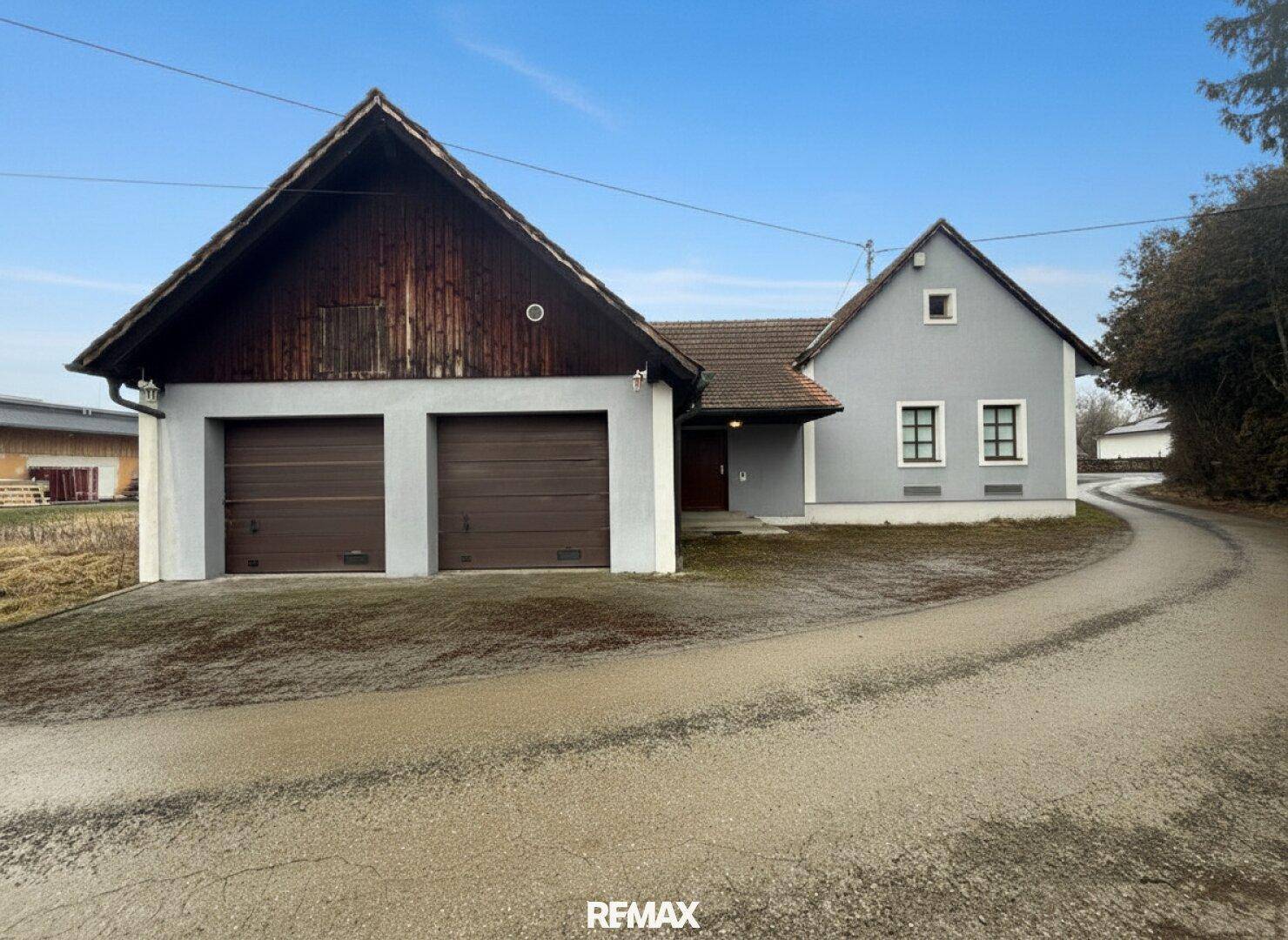 Wohnhaus mit Doppelgarage und Zufahrt in ländlicher Umgebung.