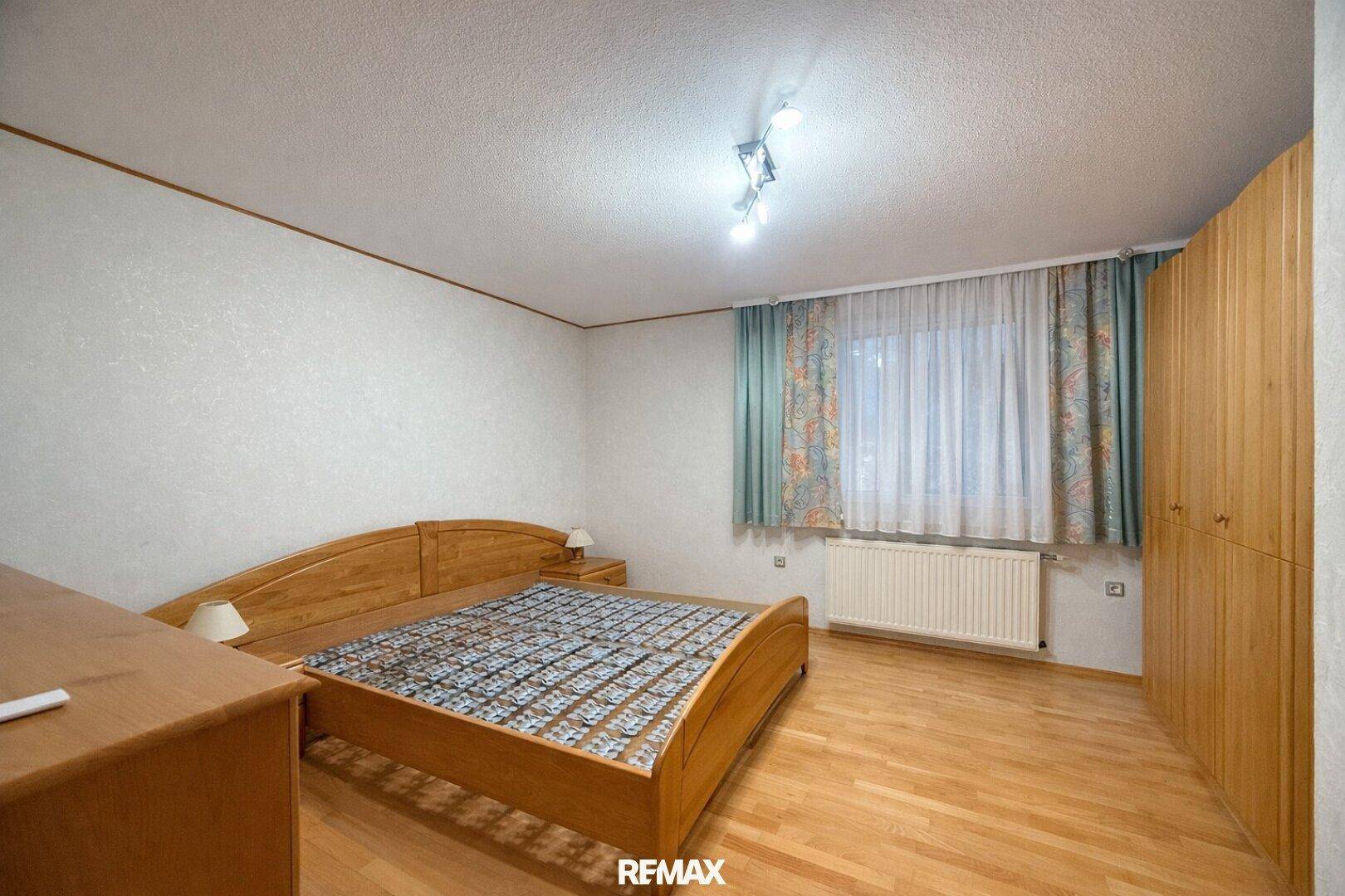 Schlafzimmer mit Holzbett, Einbauschränken und hellem Holzboden.