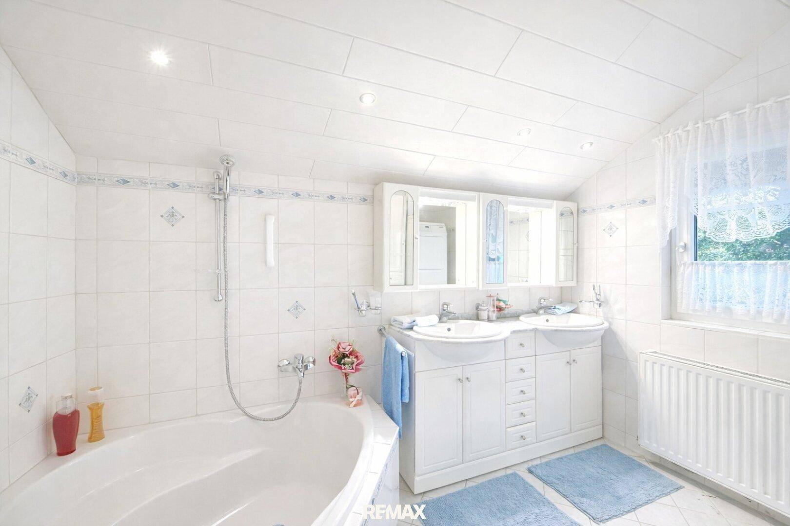 Helles Badezimmer im Dachgeschoss mit Doppelwaschbecken, Badewanne und Fenster.