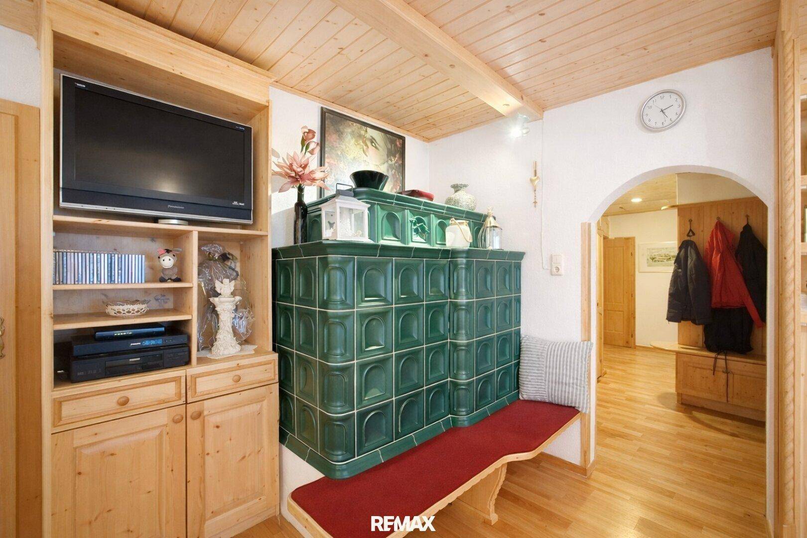 Gemütlicher Wohnbereich mit traditionellem Kachelofen und Holzboden.