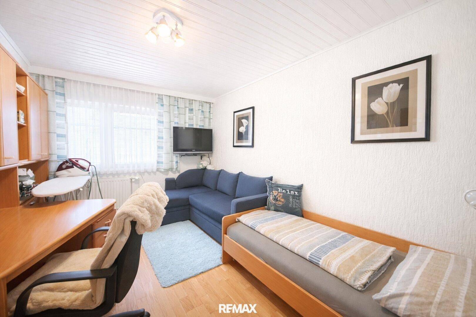 Helles Zimmer mit Holzboden, Schlafsofa und Schreibtisch, ideal als Gästezimmer.