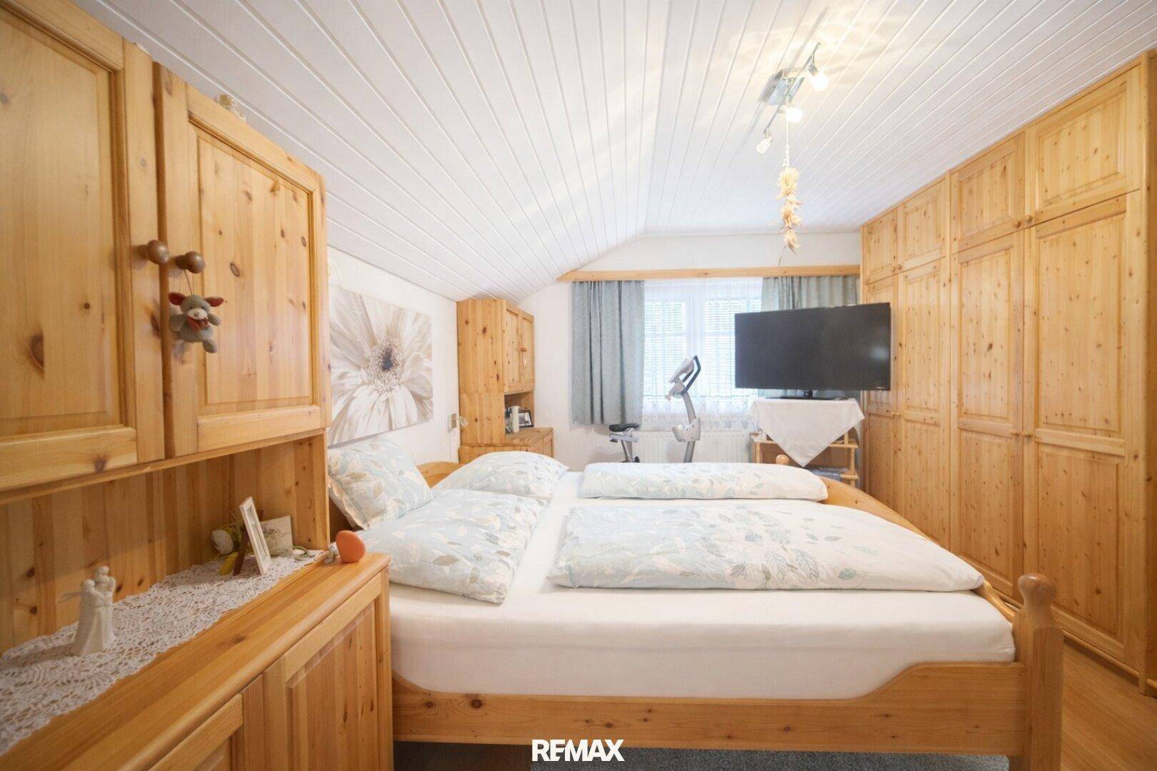 Gemütliches Schlafzimmer im Dachgeschoss mit Holzverkleidung und Einbauschränken.