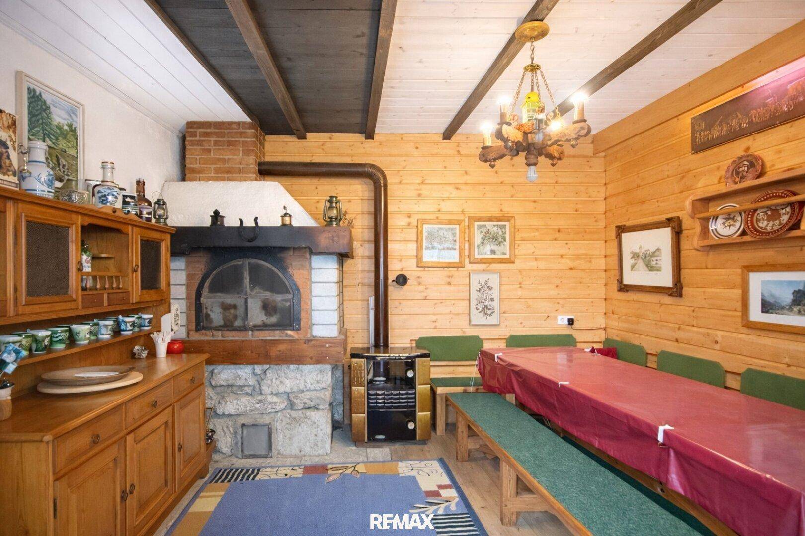 Rustikaler Essbereich mit großem Kamin, Holzwänden und langen Holzbänken.