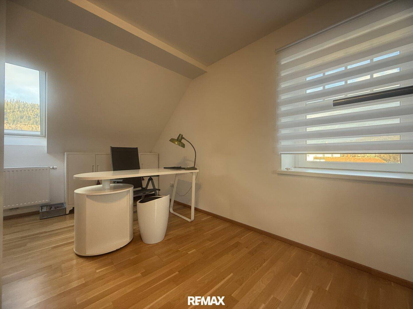 Helles Arbeitszimmer mit Holzfußboden, Schreibtisch und Dachschräge, ideal für Home-Office.