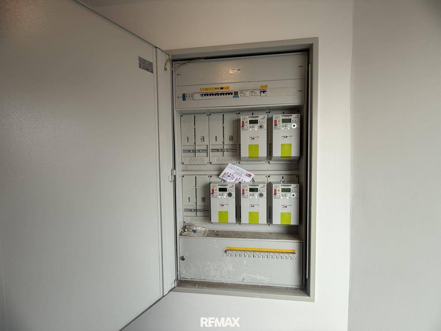Elektrischer Verteilerkasten mit mehreren Stromzählern in einem Innenraum.