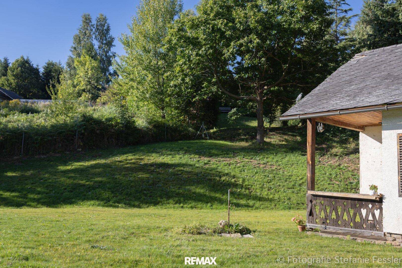 Grüne Außenanlage mit einem kleinen Haus und einer überdachten Holzveranda.