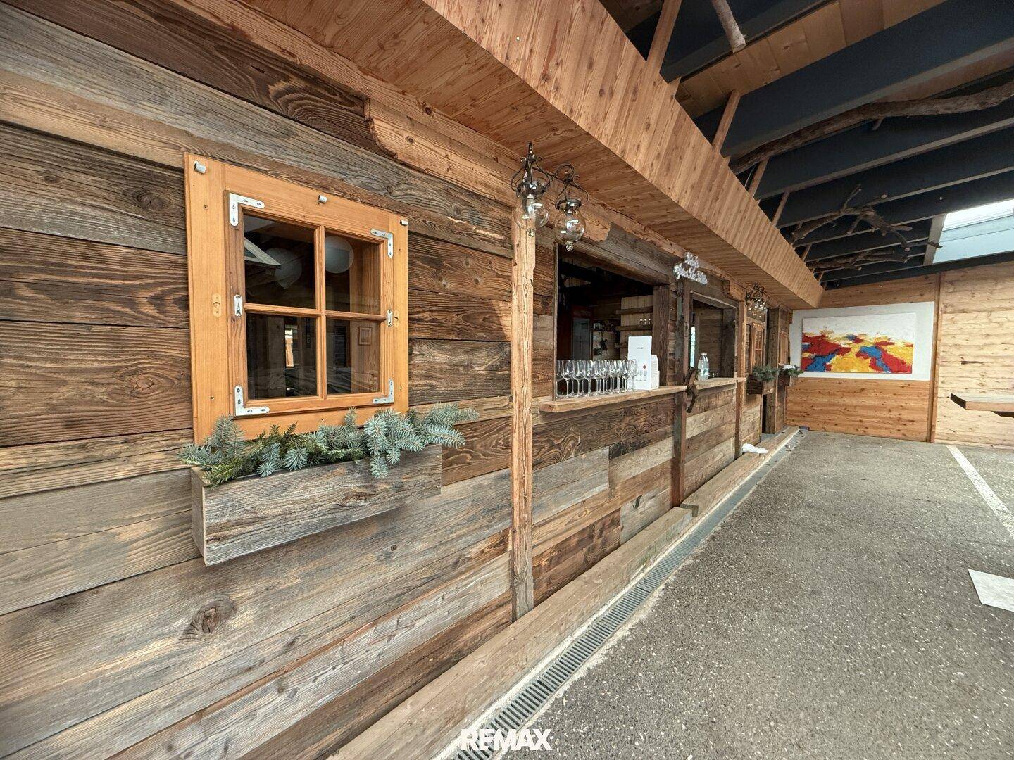 Außenwand eines Gebäudes mit einem kleinen Holzfenster und einer Theke, bereit für den Ausschank.