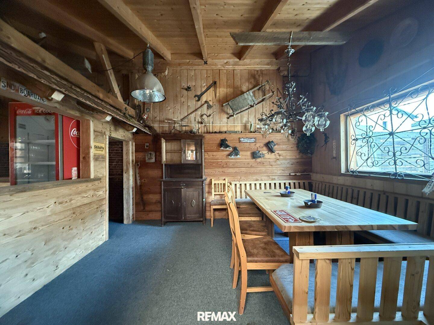 Rustikaler Essbereich mit Holzwänden, Holztischen und Bänken, dekoriert mit traditionellen Elementen.