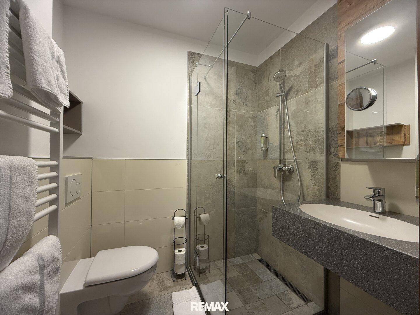 Modernes Badezimmer mit begehbarer Dusche, wandhängendem WC und stilvollem Waschtisch.