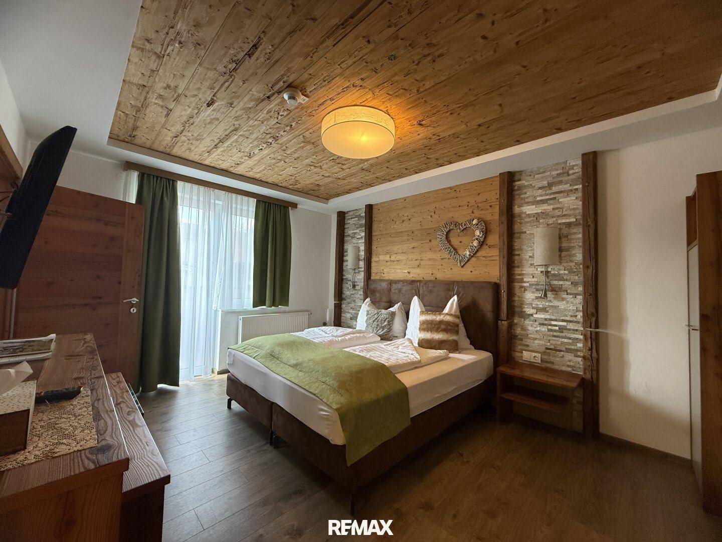 Komfortables Schlafzimmer mit Holzboden, Holzwänden und einem Doppelbett, dekoriert im Landhausstil.