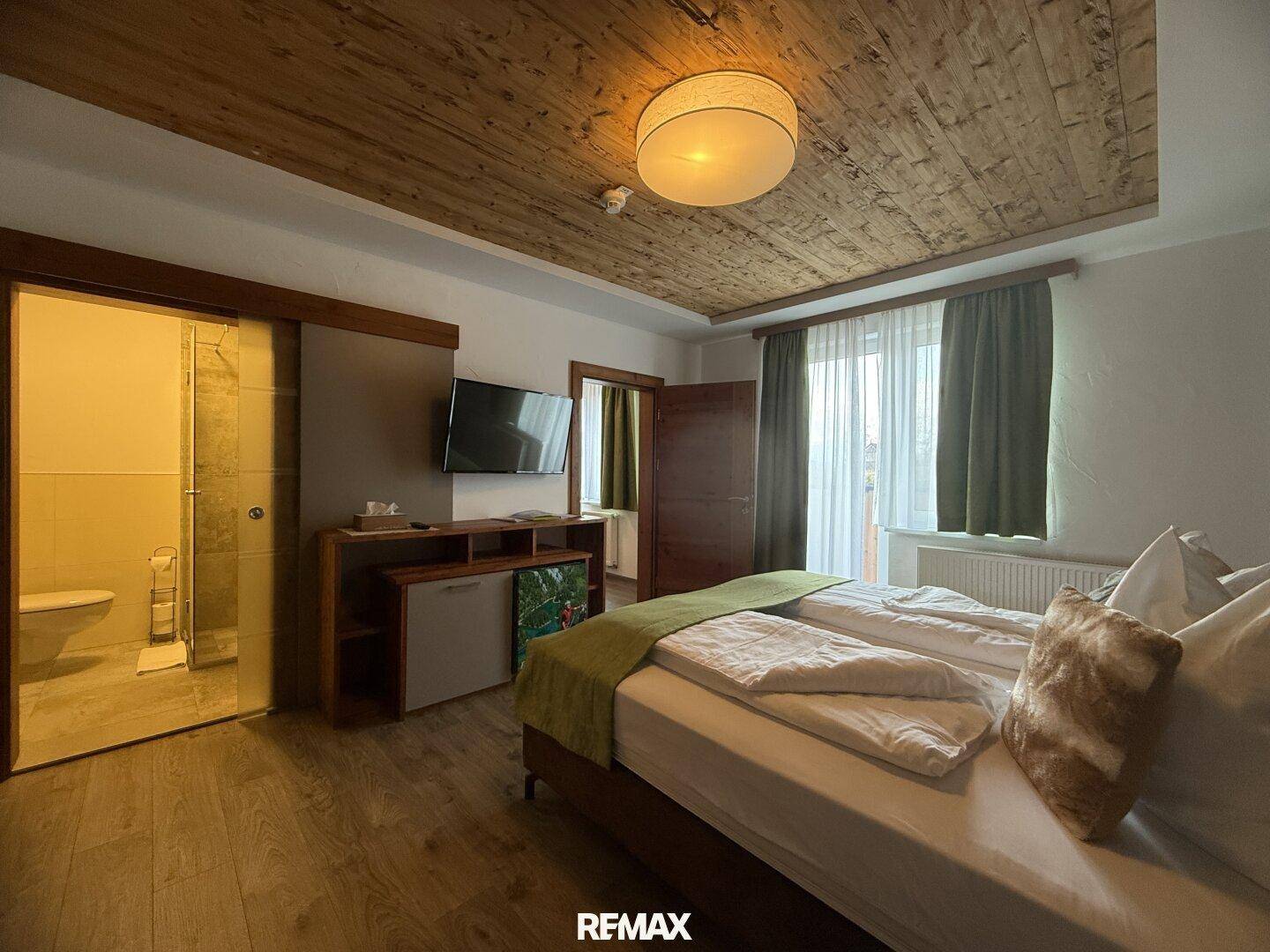 Helles Schlafzimmer mit Holzboden, Holzwänden und einem Doppelbett, mit Blick auf das Fenster.