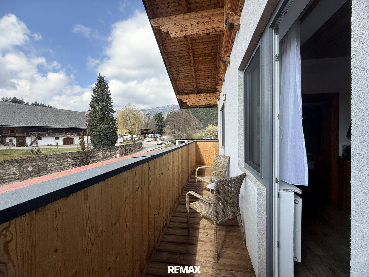 Geräumiger Balkon mit Holzboden und -decke, bietet einen weiten Blick auf die Landschaft und Berge.