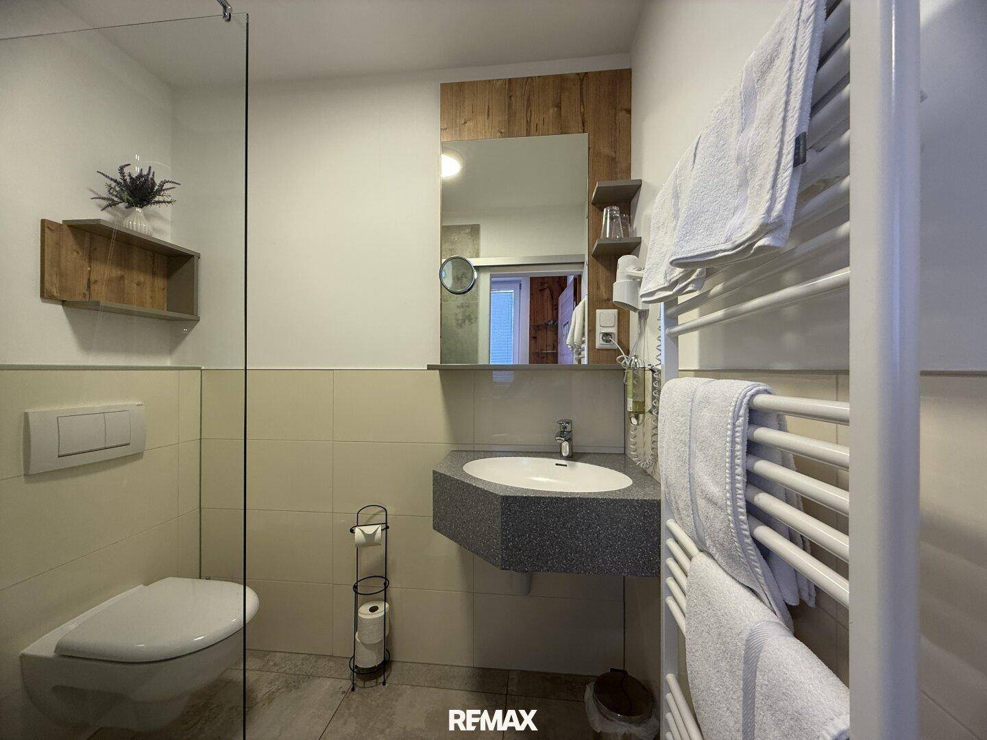 Badezimmer mit wandhängendem WC, modernem Waschbecken und einem praktischen Handtuchheizkörper.