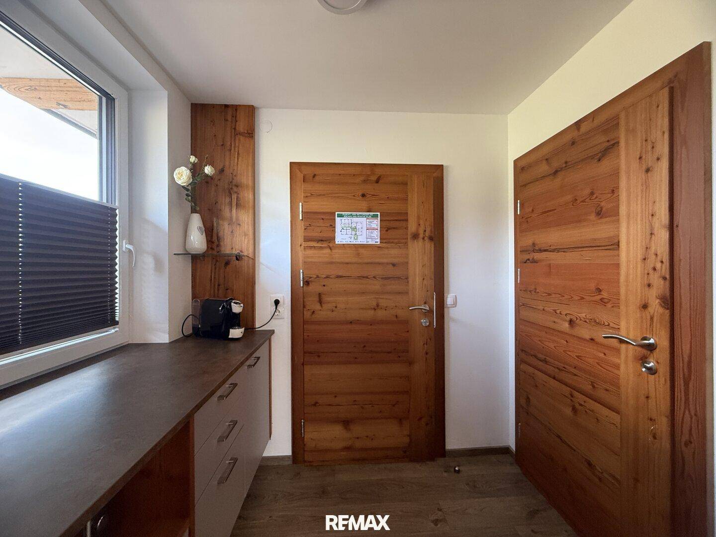 Heller Flur mit Holztüren und einer kleinen Theke, ideal für eine Kaffeestation.