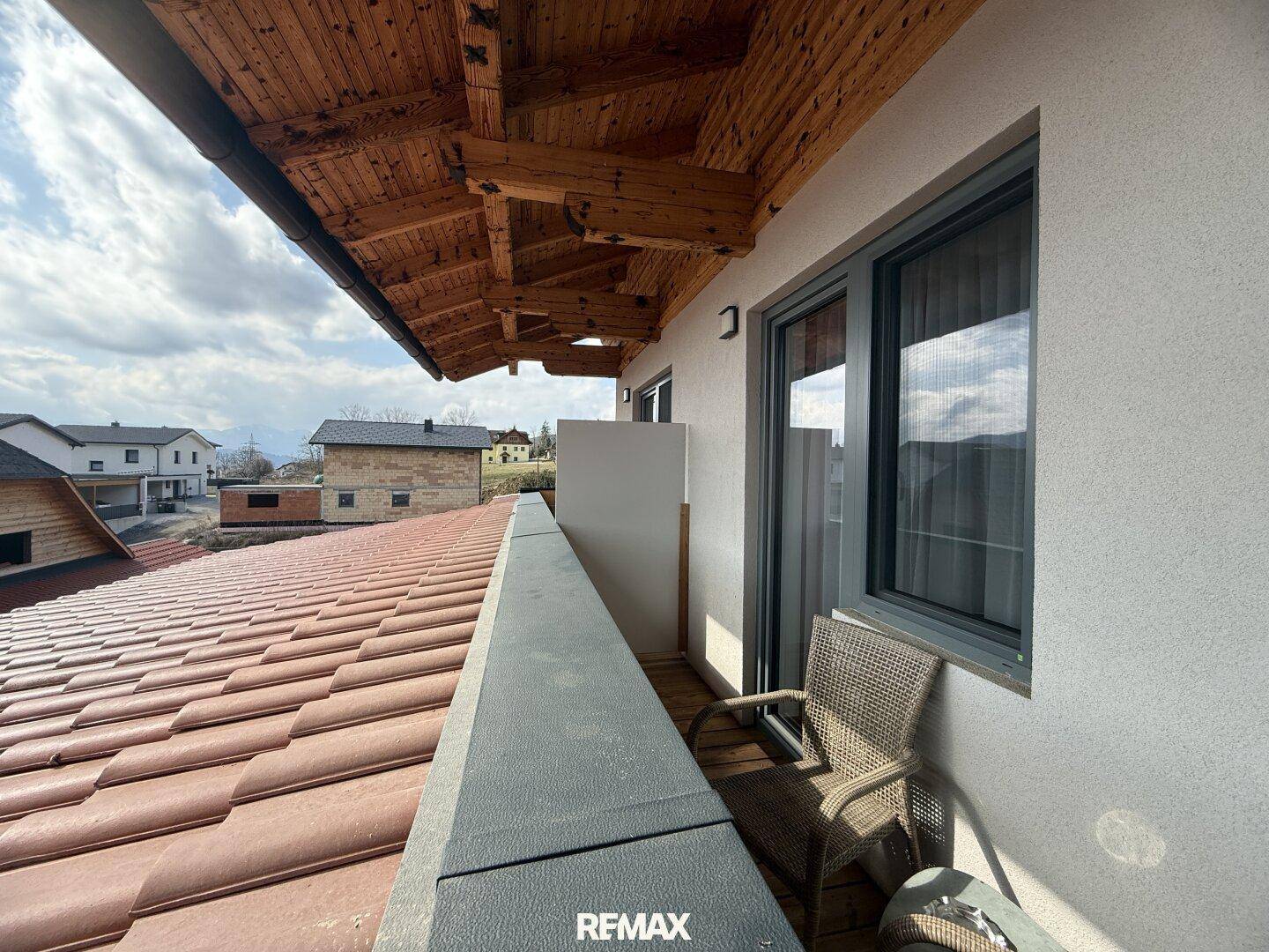 Balkon mit Ziegeldach und Blick auf die umliegenden Häuser und die Berglandschaft.
