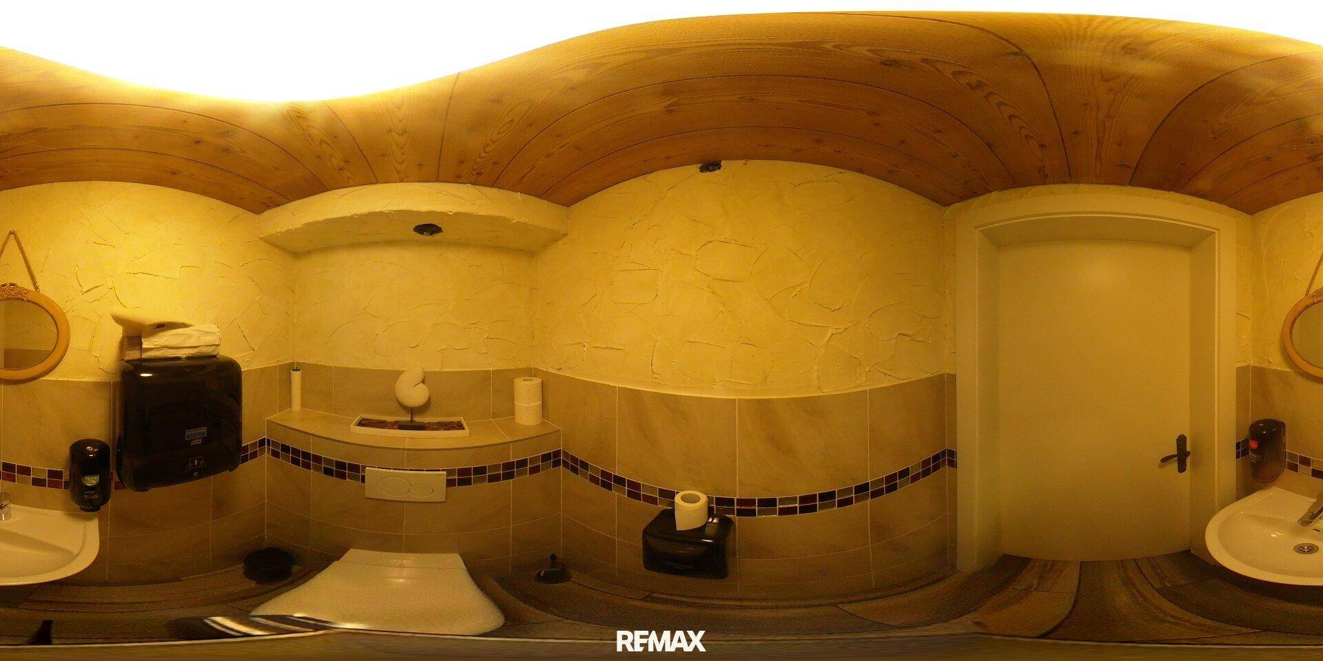 Geräumiges Badezimmer mit mehreren Waschtischen und Toiletten, ausgestattet mit Holzbalkendecke.