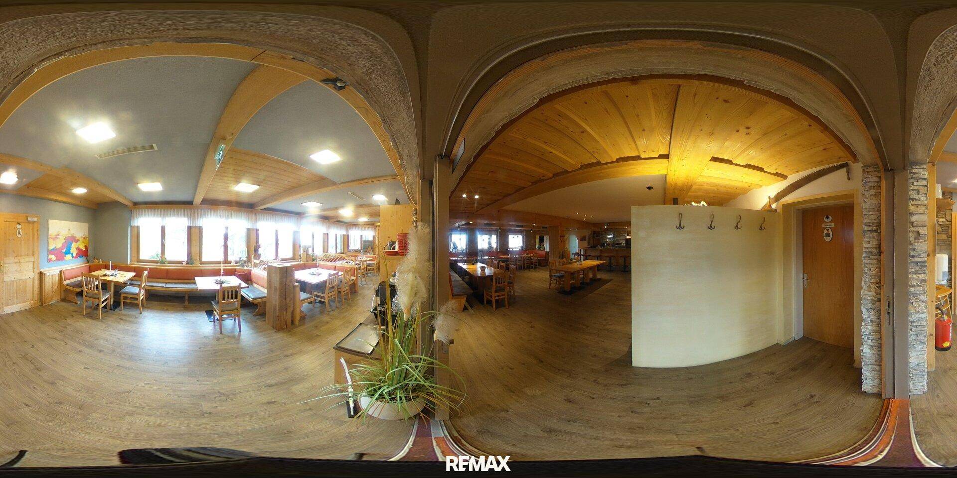 Panoramablick in einen weitläufigen Speisesaal mit verschiedenen Sitzbereichen und rustikalen Holzelementen.