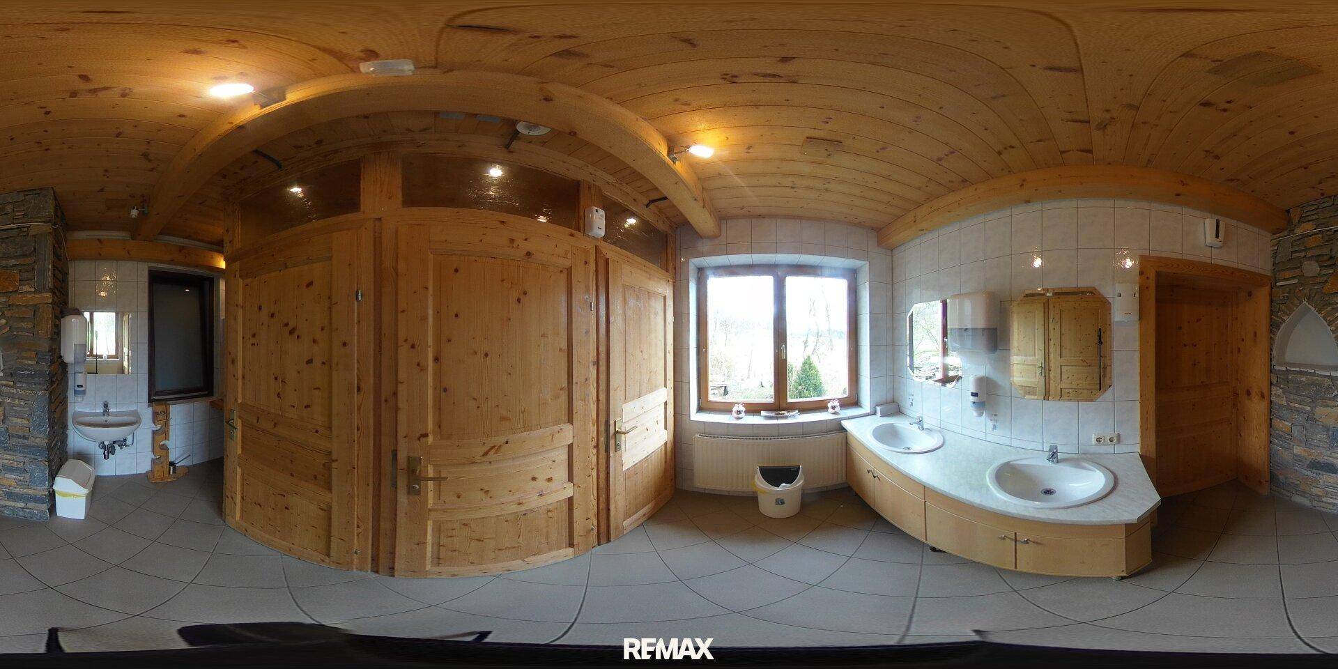 Großes Badezimmer mit mehreren Waschbecken, Holzschränken, Fliesenboden und einem Fenster.