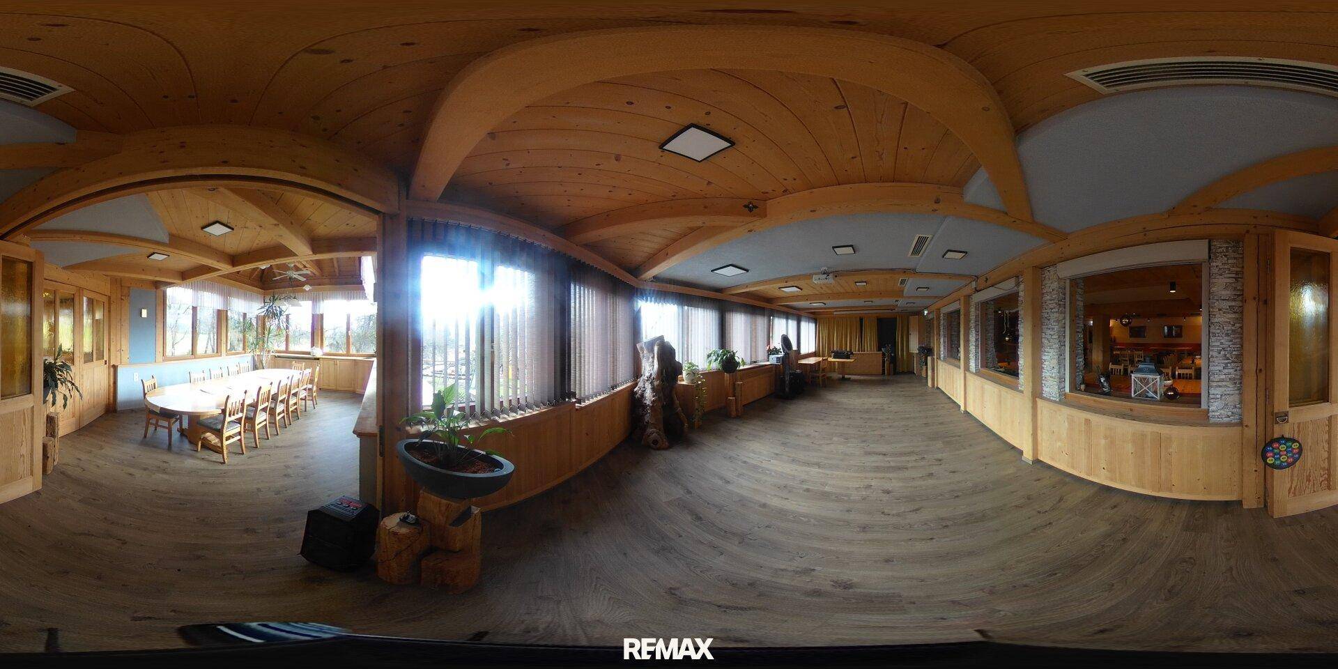 Großer Speisesaal mit Holzbalkendecke und -wänden, ausgestattet mit vielen Tischen und Stühlen.