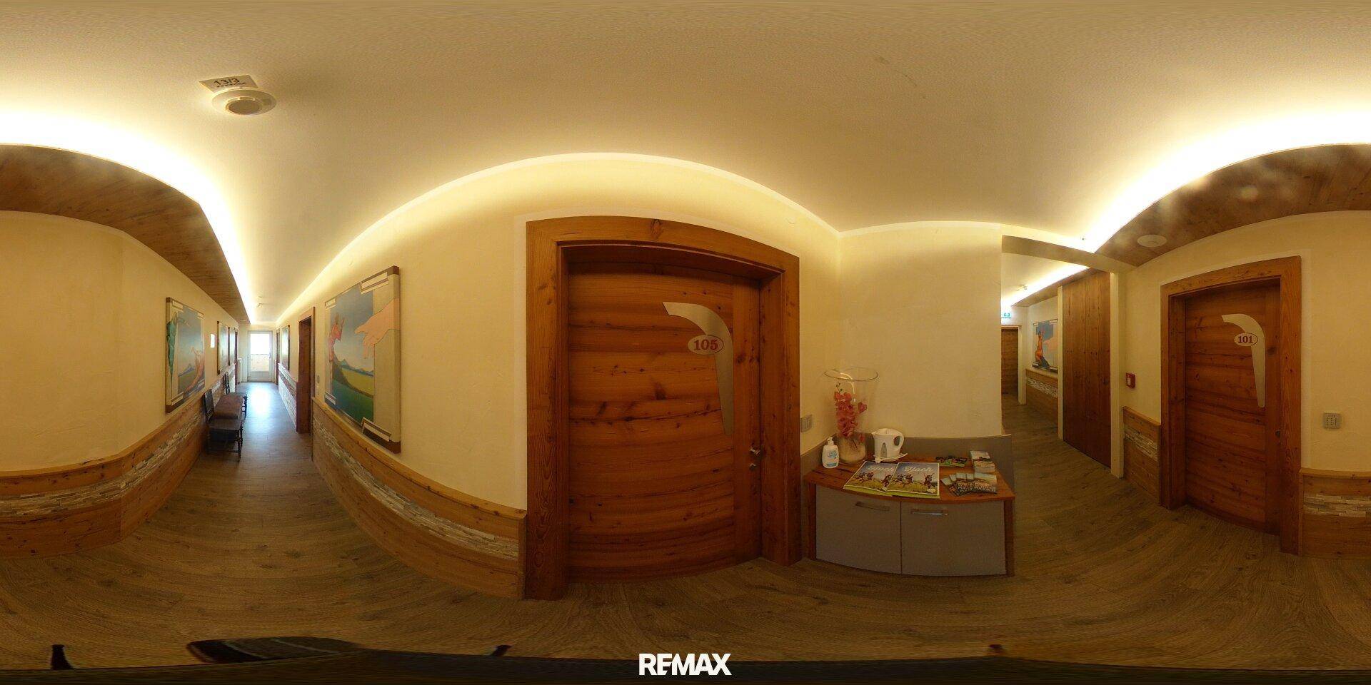 Panoramablick in einen Flur mit Holztüren, Holzvertäfelung und einer kleinen Servierstation.