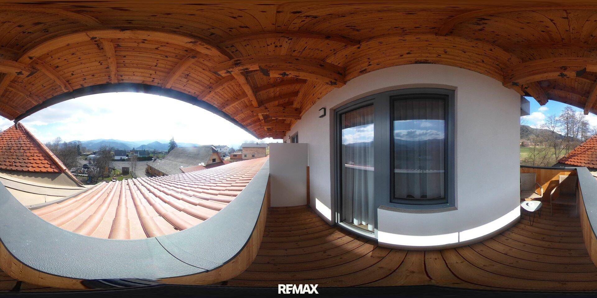 Balkon mit Holzboden und -decke, bietet einen weiten Panoramablick auf die Berge und Landschaft.