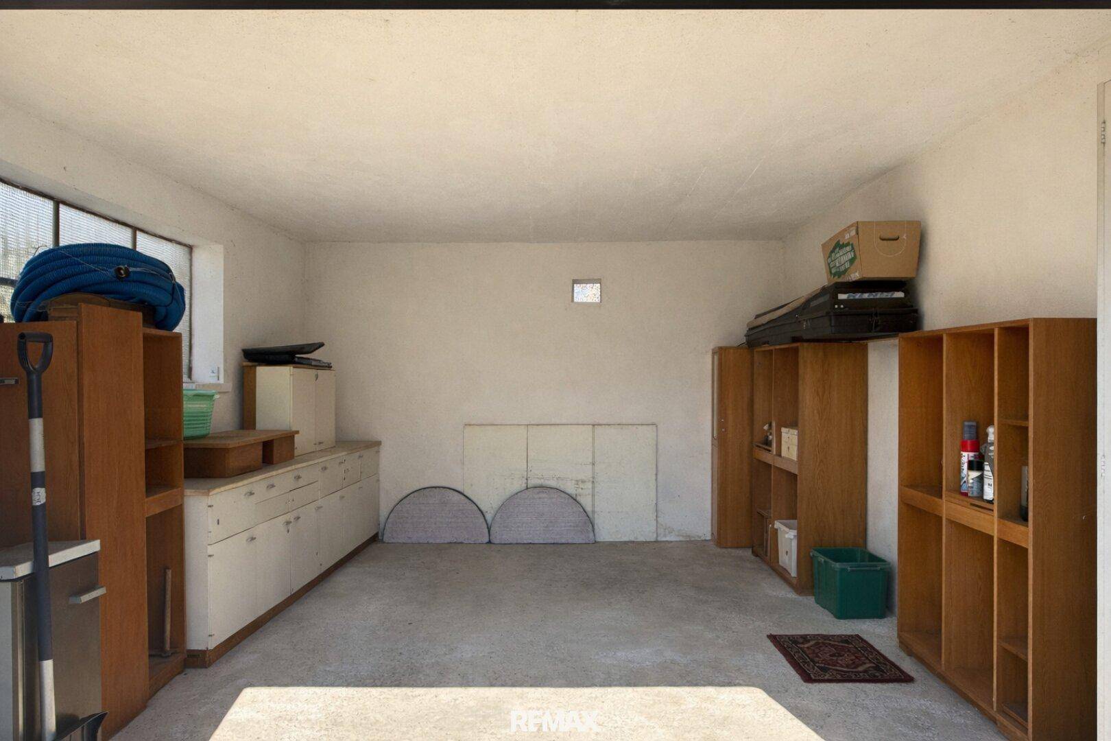 Geräumige Garage mit Betonboden und Regalen für Lagerzwecke.