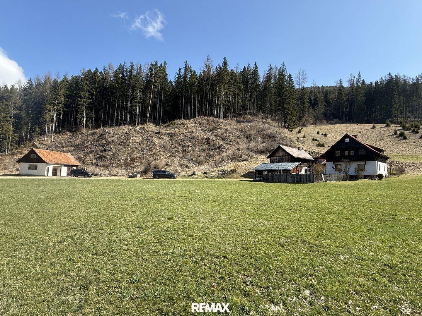 Weitläufiges Grundstück mit mehreren Gebäuden, umgeben von Wald und Wiesen in alpiner Umgebung.