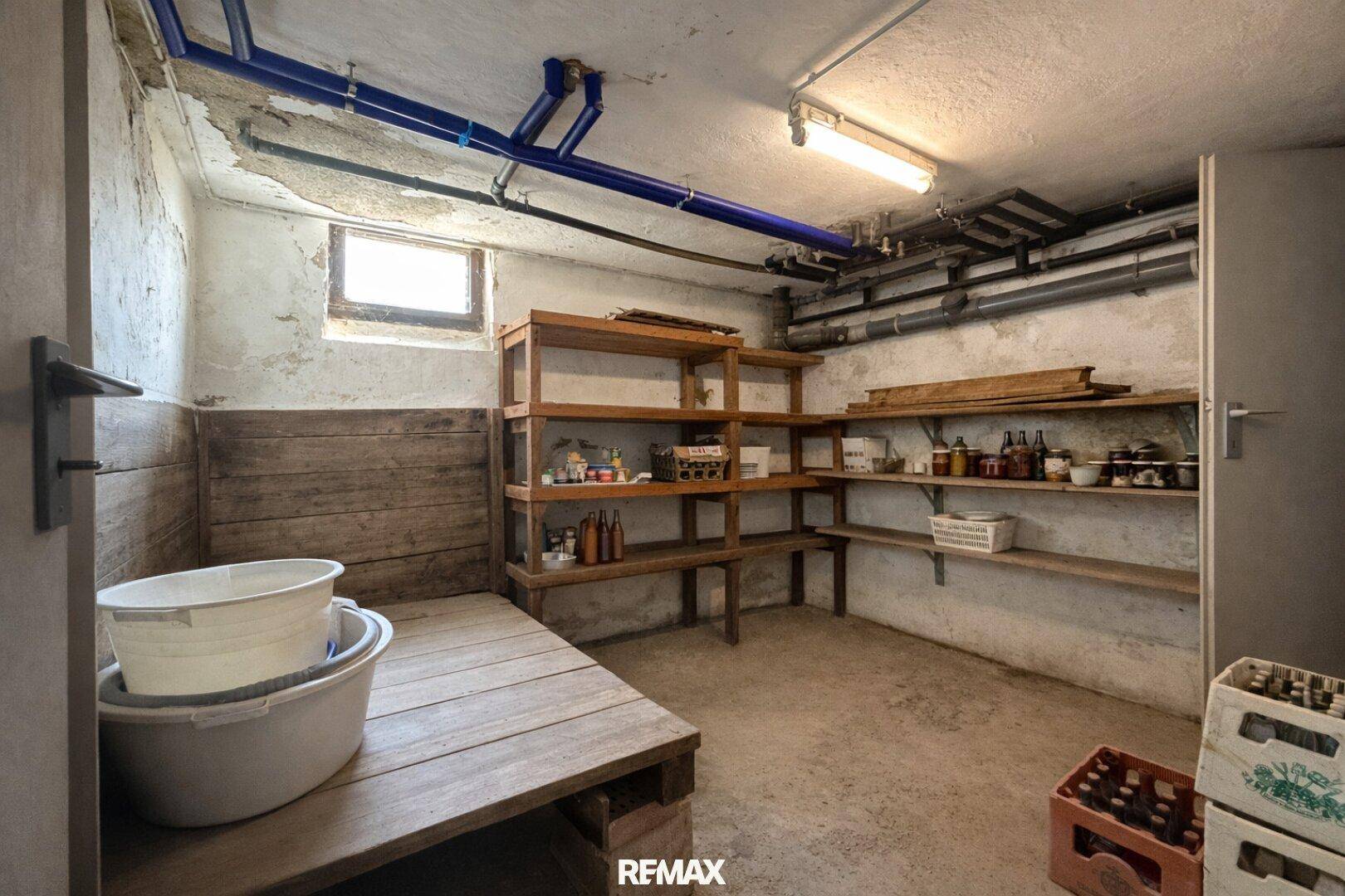 Lagerraum im Keller mit Holzregalen und sichtbaren Rohren an der Decke.