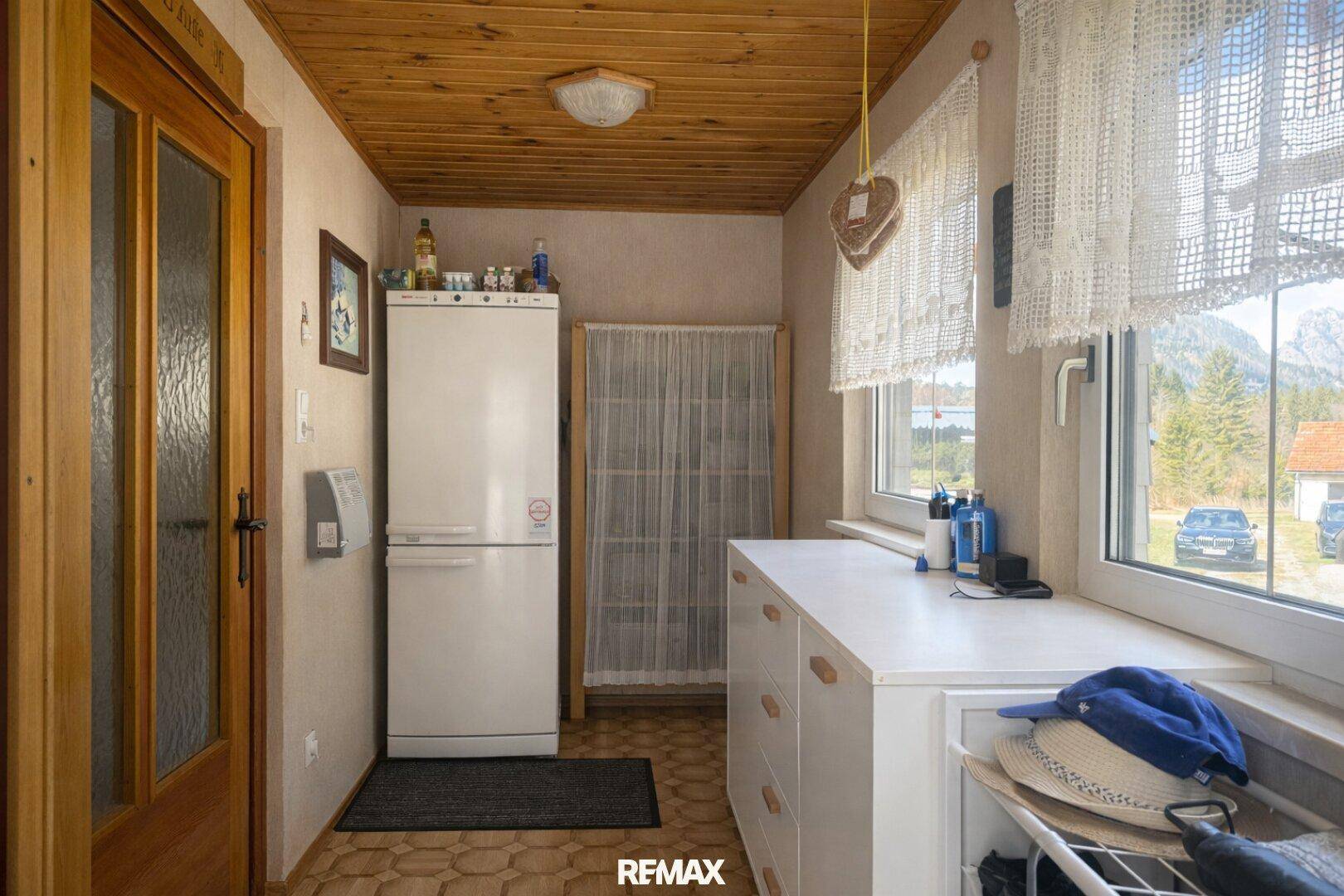 Heller Hauswirtschaftsraum mit Fenster, Kühlschrank und Ablageflächen.