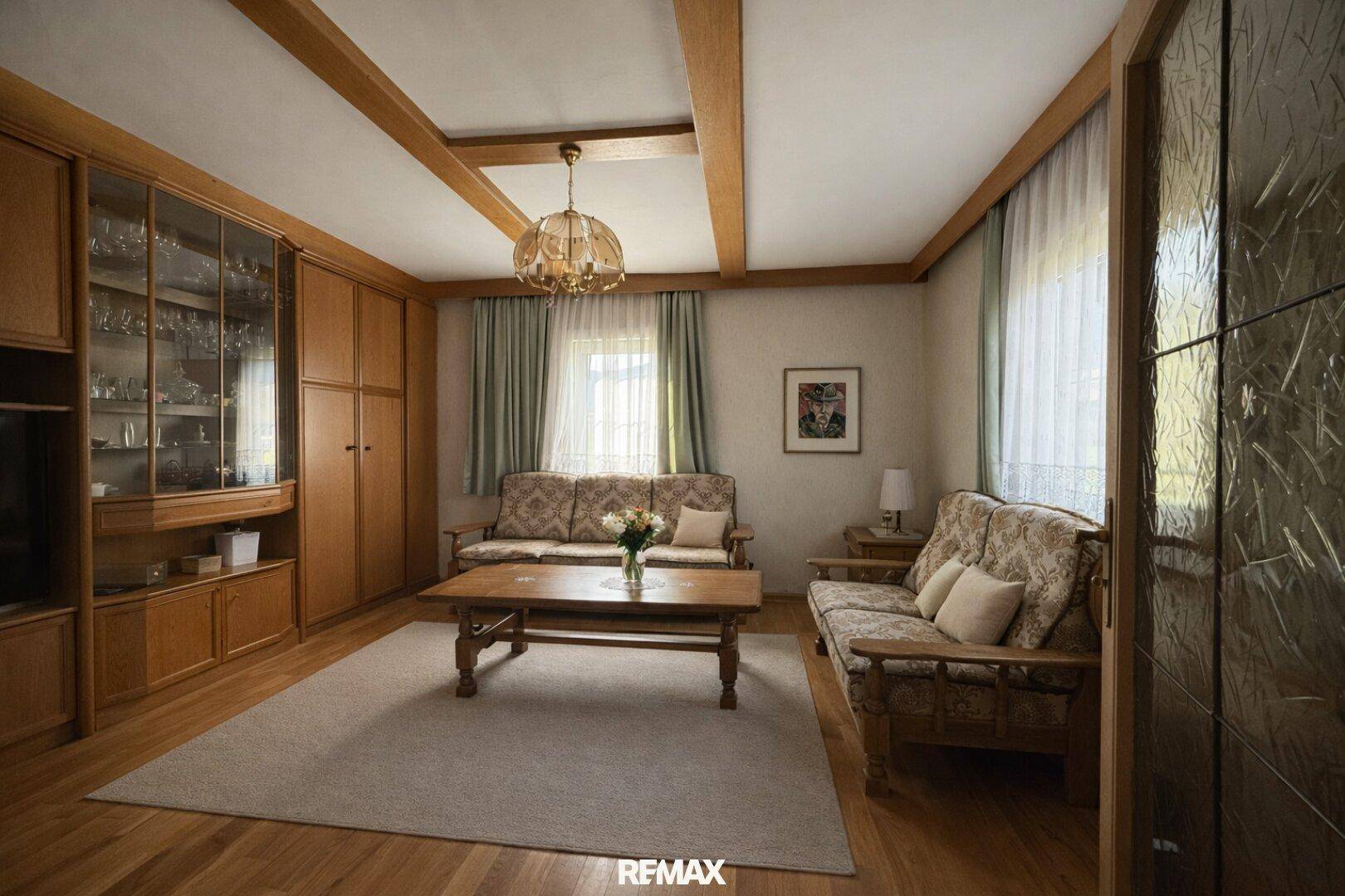 Geräumiges Wohnzimmer mit Holzbalkendecke, Parkettboden und traditionellen Möbeln.