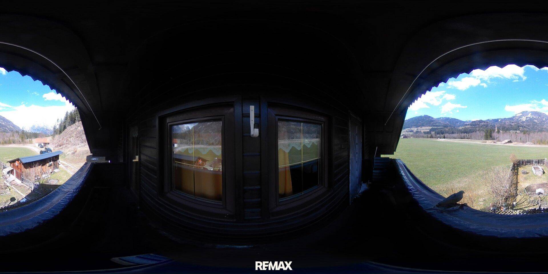 360-Grad-Ansicht von einem Balkon mit weitem Blick auf die Berglandschaft und grüne Wiesen.