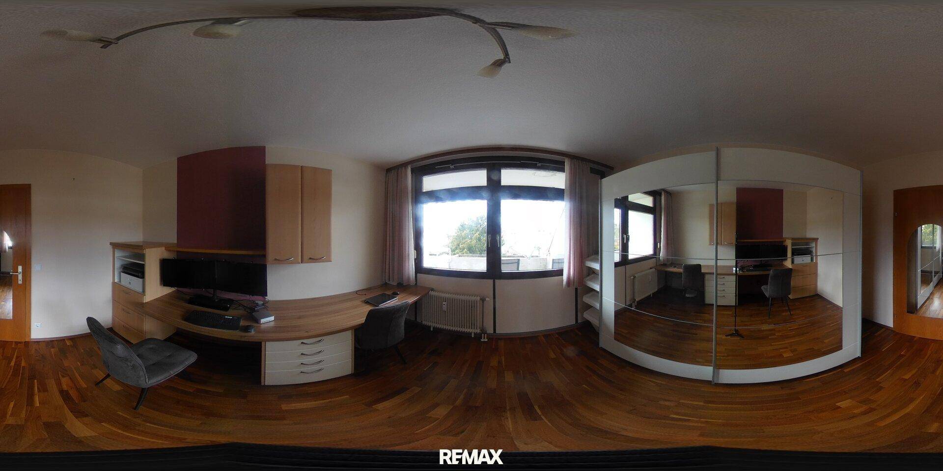 Helles Arbeitszimmer mit Holzparkett, großem Schreibtisch und Spiegelschrank.